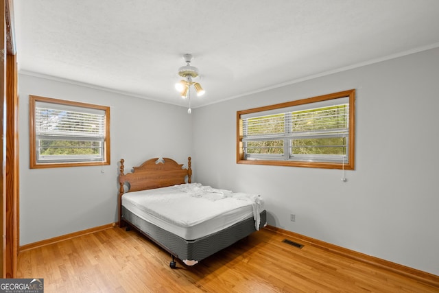 bedroom featuring ceiling fan, crown molding, and wood-type flooring