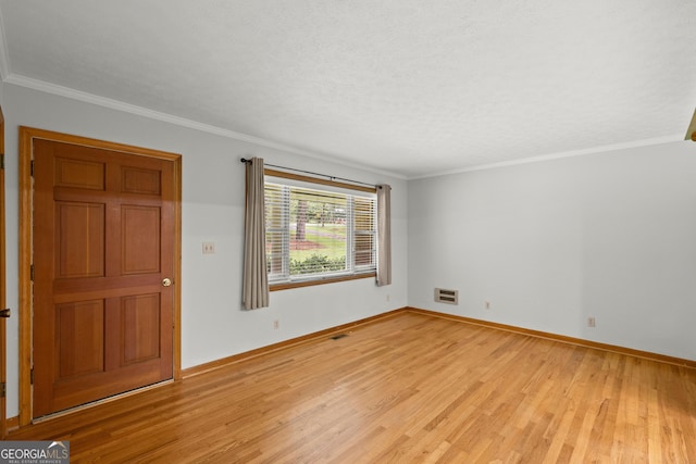 empty room with ornamental molding, a textured ceiling, and light hardwood / wood-style flooring