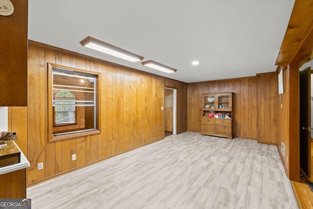 unfurnished room featuring light hardwood / wood-style flooring and wooden walls