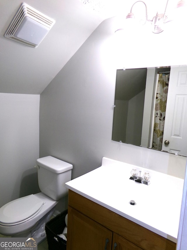 bathroom featuring vanity, toilet, and vaulted ceiling