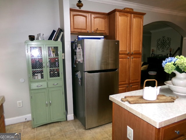 kitchen featuring stainless steel fridge, tile counters, and crown molding