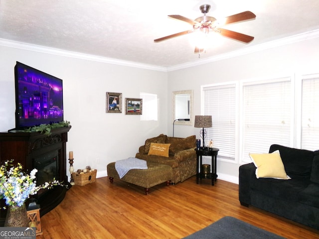 living room with a textured ceiling, ceiling fan, wood-type flooring, and crown molding