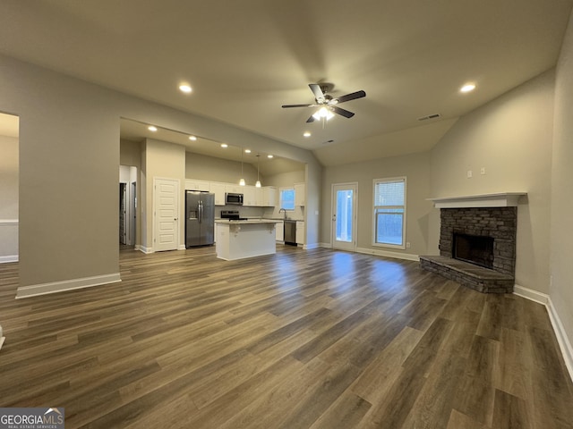 unfurnished living room featuring a fireplace, dark hardwood / wood-style flooring, ceiling fan, and lofted ceiling