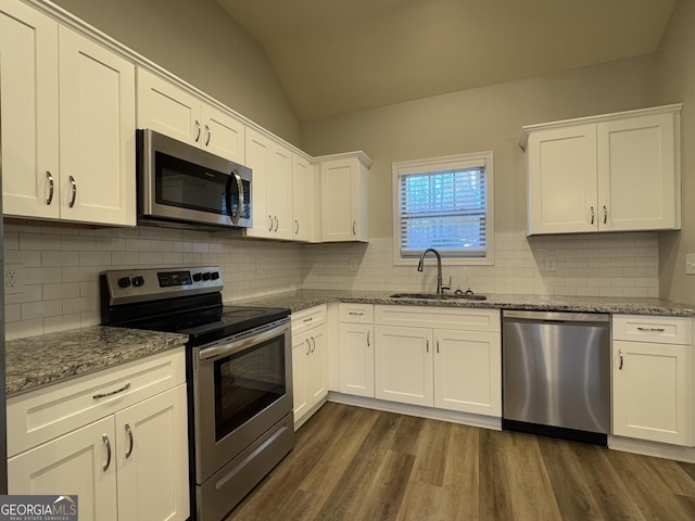 kitchen with white cabinets, appliances with stainless steel finishes, and vaulted ceiling