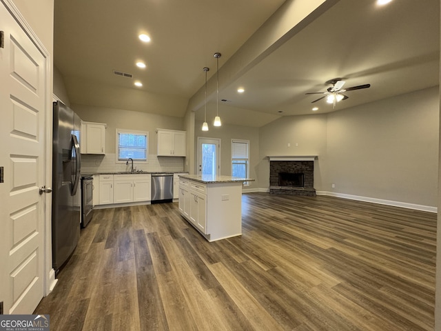 kitchen with a center island, white cabinets, vaulted ceiling, ceiling fan, and appliances with stainless steel finishes