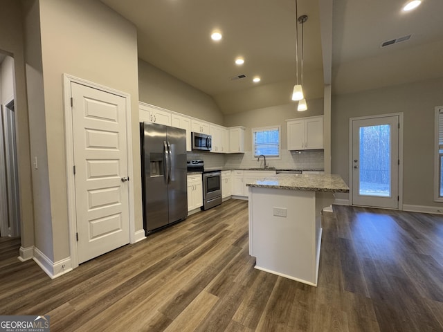 kitchen featuring decorative backsplash, stainless steel appliances, sink, a center island, and white cabinetry