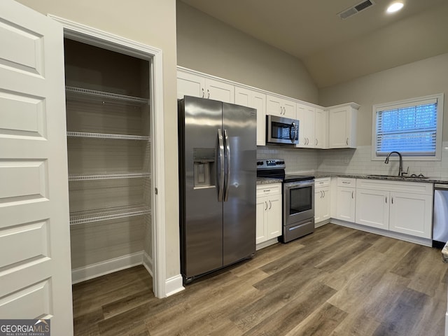 kitchen with backsplash, light stone counters, stainless steel appliances, sink, and white cabinets