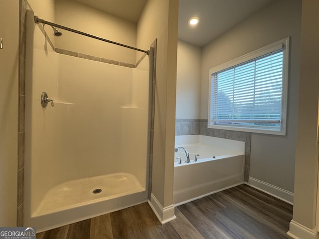 bathroom with hardwood / wood-style flooring and independent shower and bath