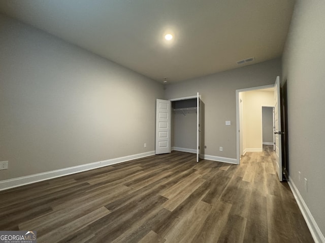 unfurnished bedroom with dark hardwood / wood-style floors and a closet