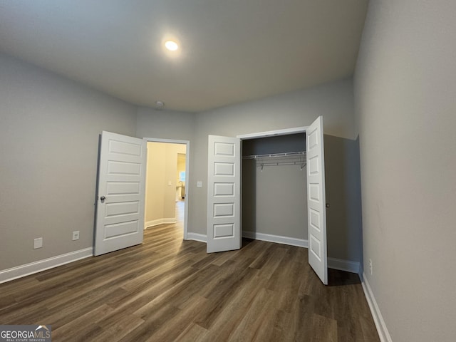 unfurnished bedroom featuring dark hardwood / wood-style flooring and a closet