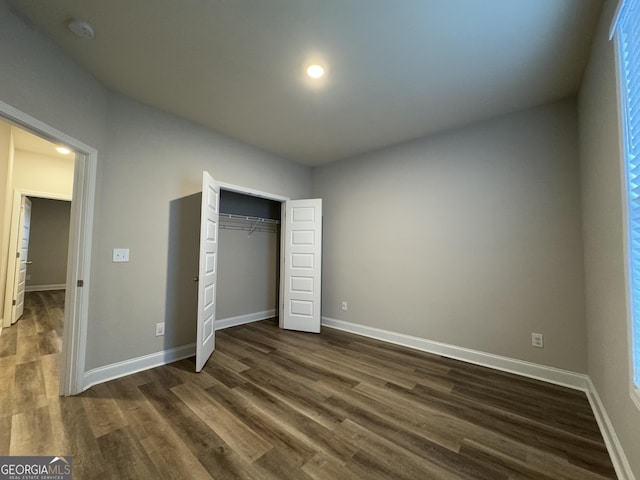 unfurnished bedroom featuring a closet and dark wood-type flooring