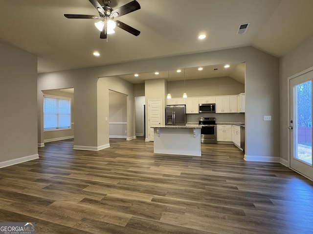 kitchen featuring stainless steel appliances, a kitchen island, decorative light fixtures, lofted ceiling, and white cabinets