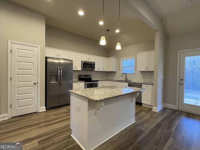 kitchen with stainless steel appliances, a kitchen island, white cabinetry, and sink