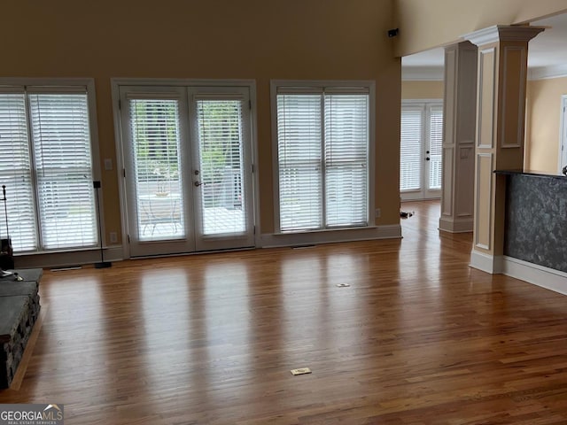 unfurnished living room with crown molding, hardwood / wood-style flooring, decorative columns, and french doors