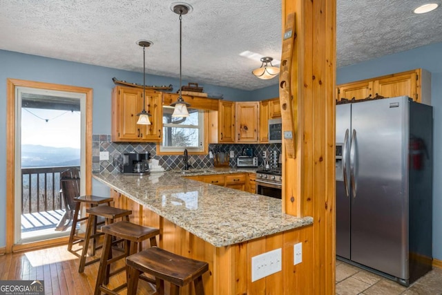 170 Walnut Rdg, Ellijay, GA 30536 - kitchen featuring appliances with stainless steel finishes, a peninsula, decorative backsplash, a textured ceiling, and light stone counters