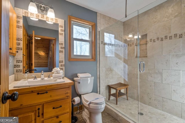 bathroom with a shower with door, vanity, and toilet