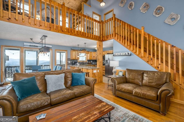 living room with a towering ceiling, a chandelier, and light wood-type flooring