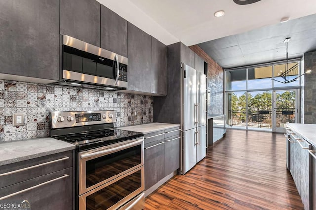 kitchen with stainless steel appliances, a wall of windows, dark hardwood / wood-style flooring, a notable chandelier, and pendant lighting