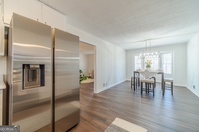 dining space featuring a notable chandelier, dark hardwood / wood-style flooring, and a textured ceiling