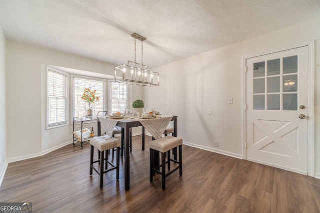 dining area with a textured ceiling and dark wood-type flooring