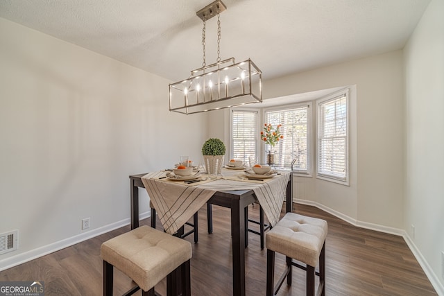 dining area with a textured ceiling and dark hardwood / wood-style flooring