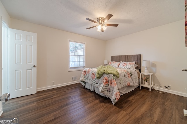 bedroom with a textured ceiling, dark hardwood / wood-style floors, and ceiling fan