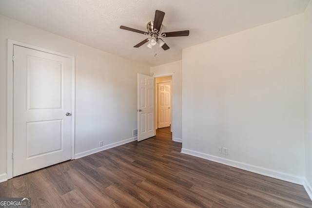 empty room featuring a textured ceiling, ceiling fan, and dark wood-type flooring