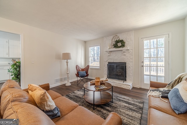 living room with a wealth of natural light, a fireplace, and dark wood-type flooring