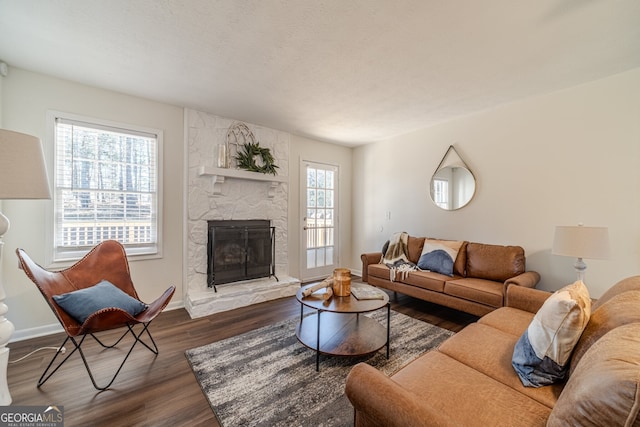 living room featuring a stone fireplace and dark hardwood / wood-style flooring