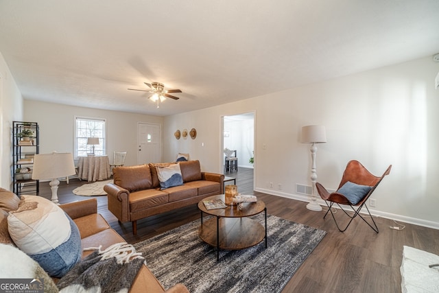 living room featuring ceiling fan and dark wood-type flooring