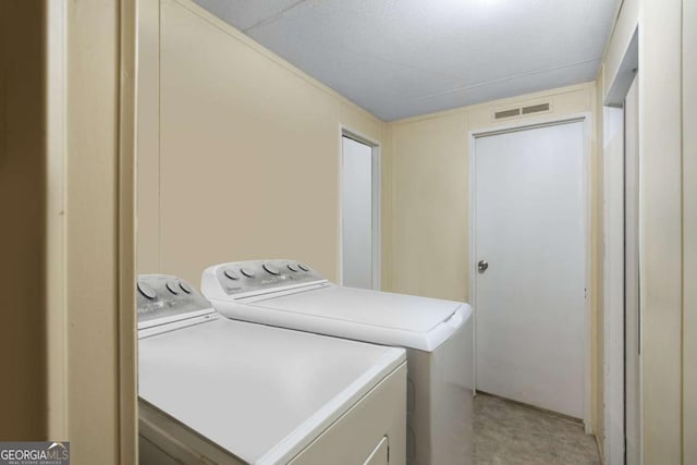 laundry room featuring light colored carpet, washer and dryer, and a textured ceiling