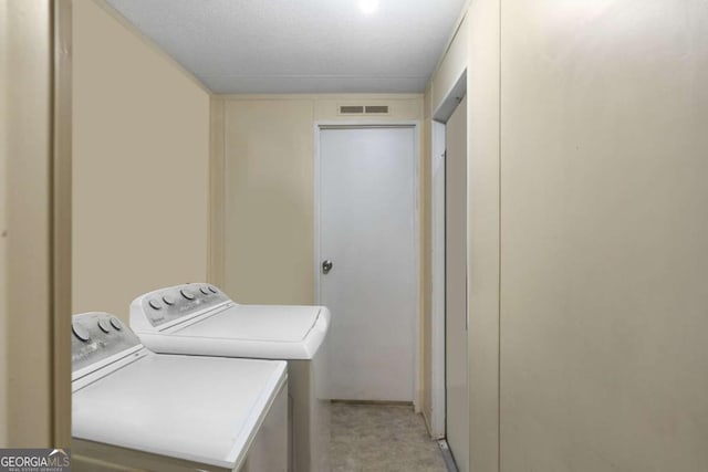 washroom featuring a textured ceiling and washing machine and dryer