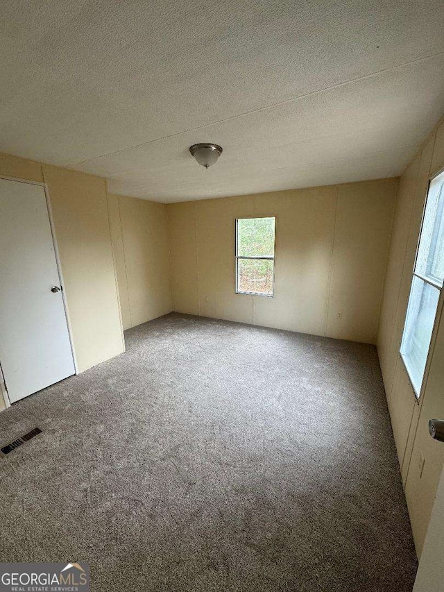 carpeted empty room with a textured ceiling