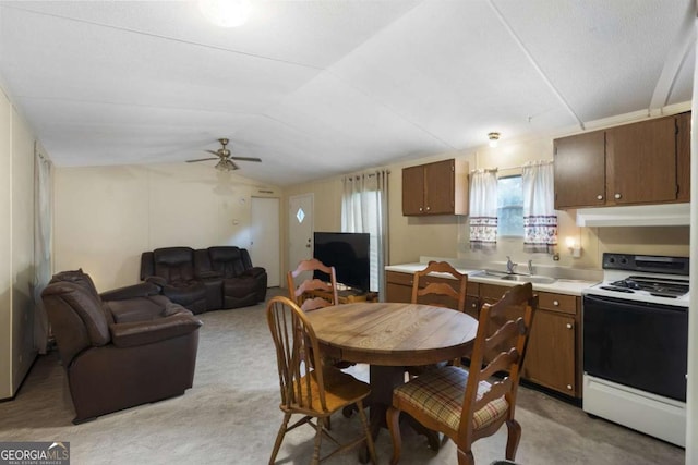 dining space featuring ceiling fan, light colored carpet, sink, and vaulted ceiling