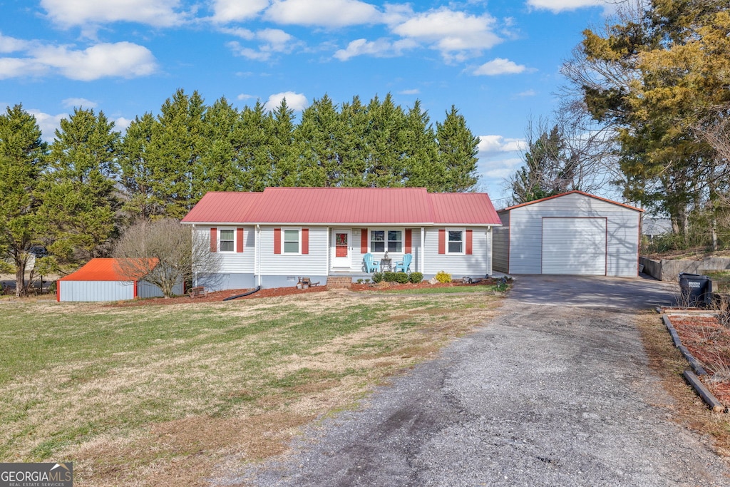 ranch-style home with a garage, covered porch, an outdoor structure, and a front lawn