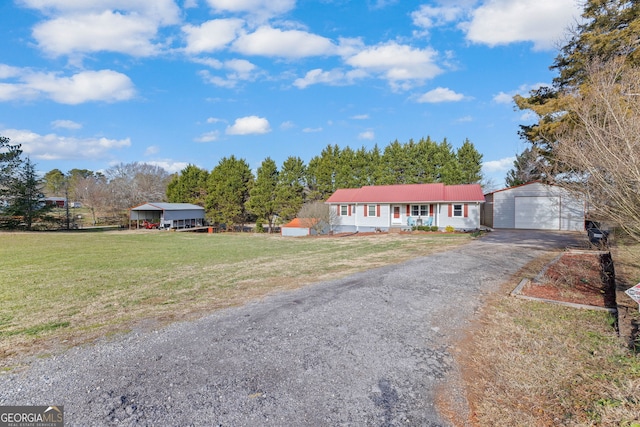 ranch-style house featuring covered porch, a garage, a carport, a front yard, and an outdoor structure