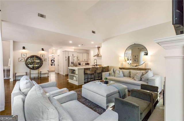 living room featuring vaulted ceiling, dark hardwood / wood-style flooring, and sink