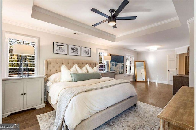 bedroom featuring ceiling fan, dark hardwood / wood-style flooring, crown molding, and a tray ceiling