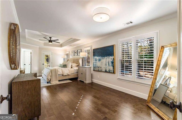 bedroom featuring dark wood-type flooring, ceiling fan, a tray ceiling, and crown molding