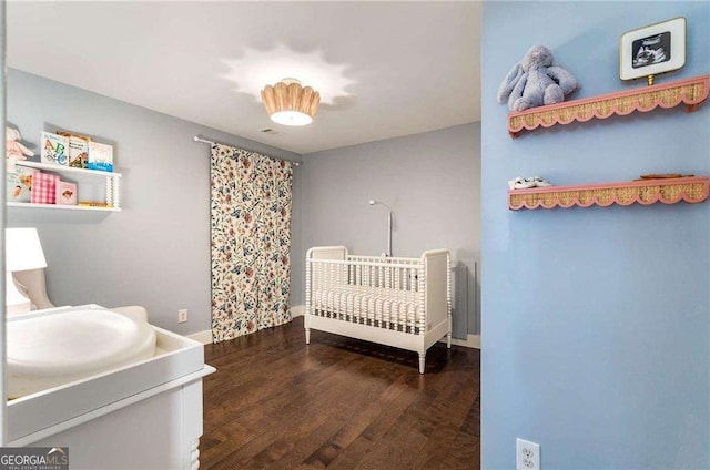 bedroom with sink, dark hardwood / wood-style floors, and a nursery area