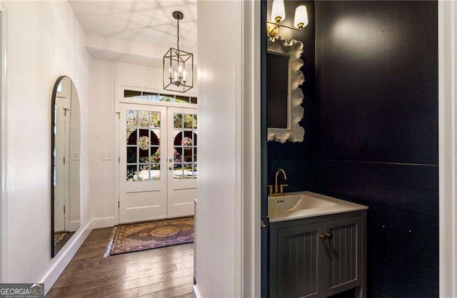 bathroom with a notable chandelier, french doors, hardwood / wood-style floors, and vanity