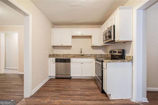 kitchen featuring appliances with stainless steel finishes, dark stone counters, sink, white cabinets, and dark hardwood / wood-style floors