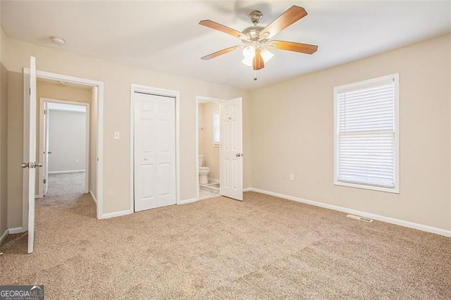 unfurnished bedroom featuring connected bathroom, light colored carpet, and ceiling fan