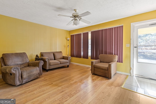 living room with a textured ceiling, light hardwood / wood-style floors, and ceiling fan