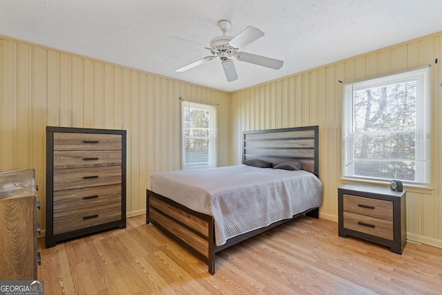 bedroom featuring multiple windows, ceiling fan, light hardwood / wood-style flooring, and a textured ceiling