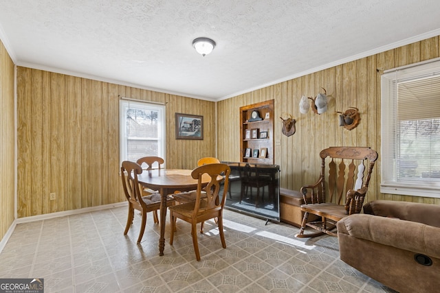 dining room with a textured ceiling, crown molding, and wood walls