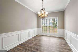 unfurnished dining area with crown molding, dark hardwood / wood-style flooring, and a notable chandelier