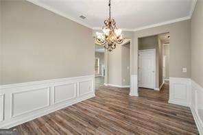 unfurnished dining area with crown molding, dark wood-type flooring, and a chandelier