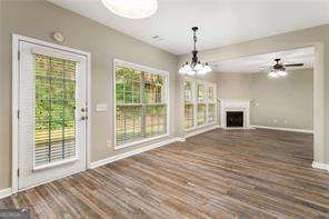 unfurnished living room featuring plenty of natural light, dark wood-type flooring, and ceiling fan with notable chandelier