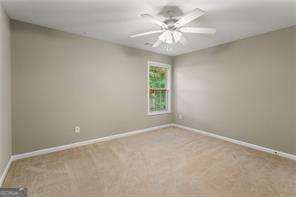 carpeted spare room featuring ceiling fan